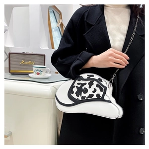 White cowboy hat crossbody bag with star pattern and cow print on silver chain strap