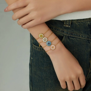 Gold starburst compass bracelets with colorful enamel charms on a female model