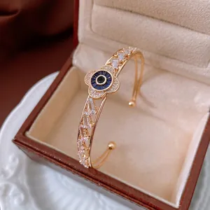 Golden open bangle with zircon flower design and blue evil eye gemstone center