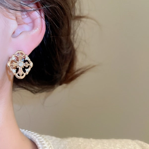 Close-up of model wearing a gold rhombus cross stud earring with sparkling zircons