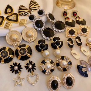 Flat lay of vintage black and gold earrings set with pearls and rhinestones on soft fabric