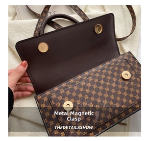 Detail view of the brown printed handbag featuring a secure gold magnetic snap closure