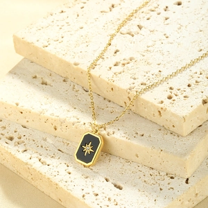 Detail of gold necklace with black rectangle pendant and starburst zircon on stone