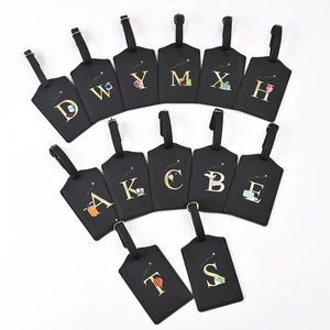Macro shot of black leather luggage tags featuring gold foil letters and travel illustrations