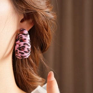 Close-up of pink leopard print fabric hoop earring worn on a model's ear