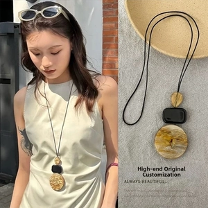Dettaglio ravvicinato e vista modella di una collana lunga con ciondolo in resina marmorizzata
