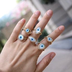 Detail of six gold-plated Evil Eye and Hamsa hand rings with zircon and shell inlay
