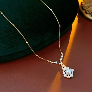 Detailed view of a gold-plated necklace with white pearls and sparkling zircon accents