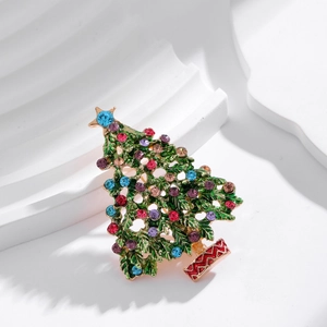Enamel Christmas tree brooch with colorful rhinestones on a white textured background