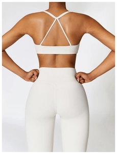 Detail of high-waist cream yoga leggings and cross-back sports bra on female model