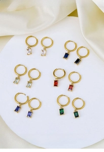 Macro shot of geometric zircon earrings in multiple colors on white silk base