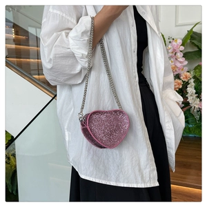 Pink heart-shaped rhinestone crossbody bag shown on model with silver metal chain strap