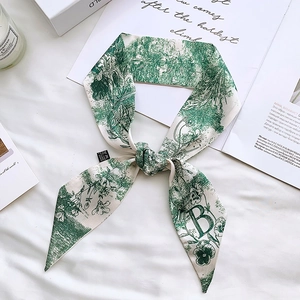 Detail of floral silk scarf with letter B on white textured background with candle decor