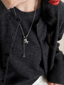 Gros plan détaillé d'un collier poney en argent minimaliste avec zircon sur gilet gris