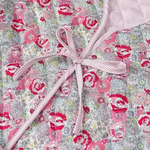 Detailed macro shot of floral quilted fabric featuring a pink rose print and striped bow tie