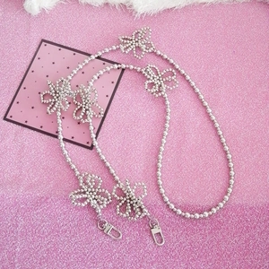 Silver bead chain with flower charms and lobster clasps on a glittery background