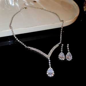 Close-up of silver-tone V-shaped pendant necklace and teardrop earrings set on a white tray