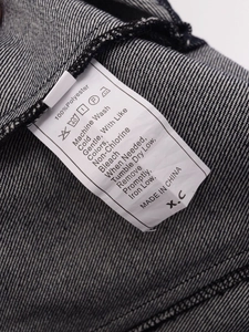 Detail des Waschetiketts mit 100% Polyester Pflegehinweisen auf Denim-Stoff