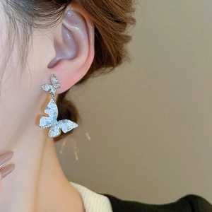 Macro view of silver butterfly earrings with marble effect inlay and zircon accents