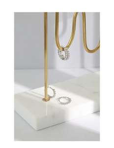 Detailed view of three silver beaded hoop earrings on a minimalist metal stand