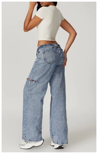 Detail shot of high-waisted wide-leg ripped denim jeans with a washed blue finish