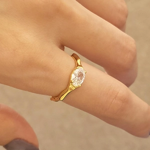 Close-up of irregular wave gold ring with oval zircon on a person's finger