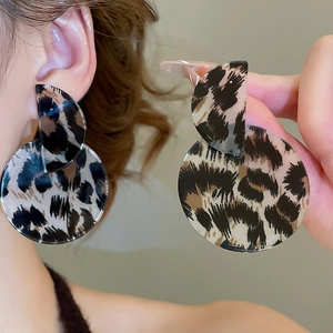 Detailed close-up of retro leopard print acrylic round drop earrings worn by a model