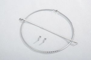 Detailed flat lay of silver titanium steel necklace and stud earrings jewelry set