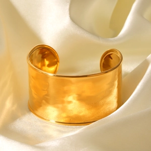 Macro detail of 18K gold plated hammered texture cuff on cream satin background