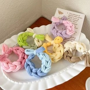 Close-up of colorful woven fabric scrunchies in a white ceramic dish, set of six