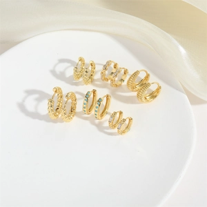 Set of six gold croissant and twisted hoop earrings displayed on a white stand