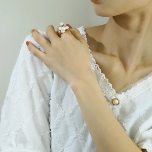 Detail view of a floral cluster ring with white pearls on a gold-plated band