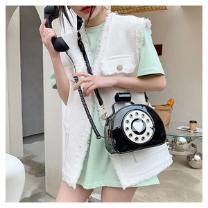 Detail of vintage telephone crossbody bag with black patent leather and white dial