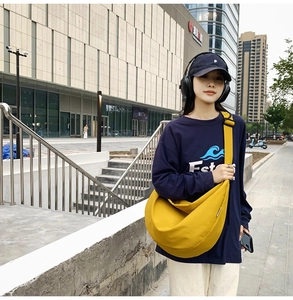Detailed view of a bright yellow large oxford fabric crescent bag with black strap