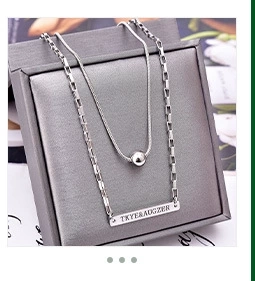 Detail of silver double layer necklace with engraved rectangular pendant on gray box