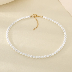 Dettaglio di collana con perle bianche e chiusura dorata su tessuto di seta