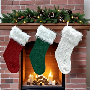 Three knitted Christmas stockings in red, green and white hanging on a cozy fireplace