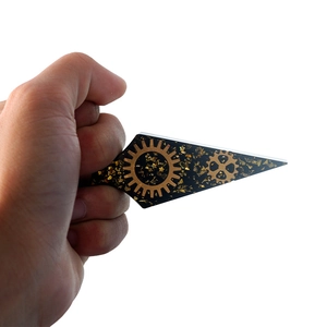 Detailed view of handmade steampunk kunai resin charm with gold foil and gears