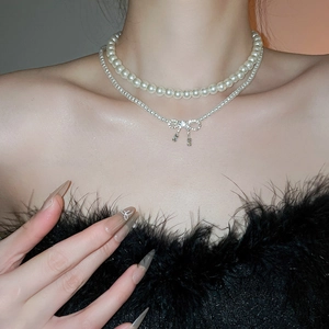 Close-up of double layer pearl necklace with sparkling rhinestone bow pendant on neck