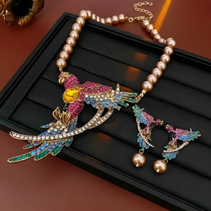 Elegant gold phoenix necklace with pink pearls and colorful rhinestones on black tray