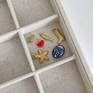 Golden baroque charms set including heart, leaf and starfish on linen jewelry tray
