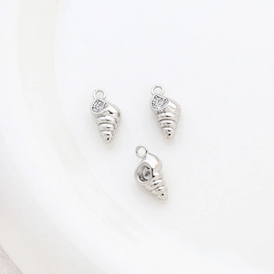 Macro detail of silver conch charms with sparkling zircon inlay for jewelry making