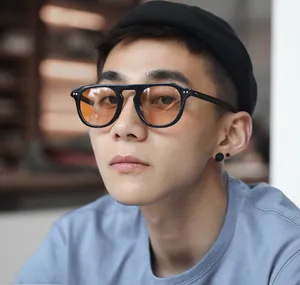 Close-up of retro black frame sunglasses with orange lenses and metal rivet details