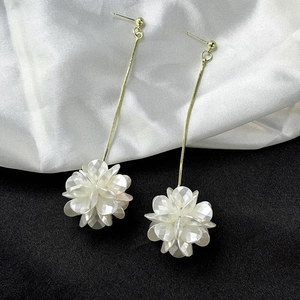 Macro detail of elegant golden chain fringe and white faceted shell flower earrings