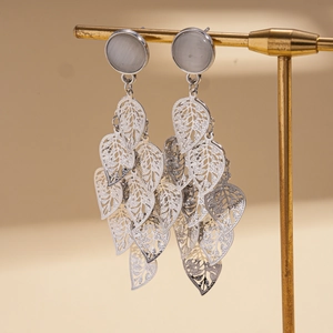Detailed macro view of silver hollow leaf tassel earrings with cat eye stone effect