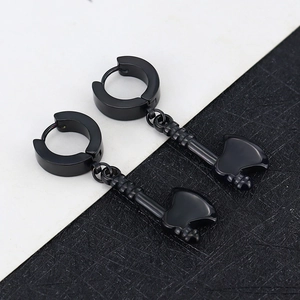Close-up of black punk style hoop earrings with axe shaped pendants in matte finish