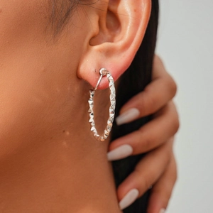Macro detail of geometric faceted silver hoop clip-on earrings with textured finish