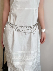 Detail view of silver layered waist chain with pearls, shells and star shaped pendants