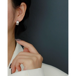 Close-up of 925 sterling silver huggie earrings with irregular vertical texture on ear