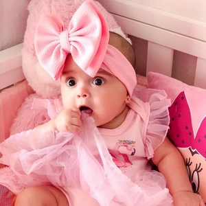 Detailed view of pink baby romper with flamingo print and matching oversized bow headband